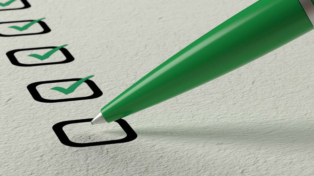 Green pen marking a checkbox on a paper checklist, indicating completed tasks