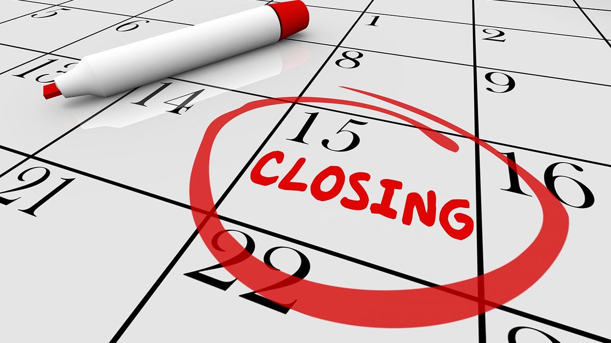 Calendar page with a red stamp circle and the word 'CLOSING' around the 15th; a white marker rests on the grid as a deadline reminder.