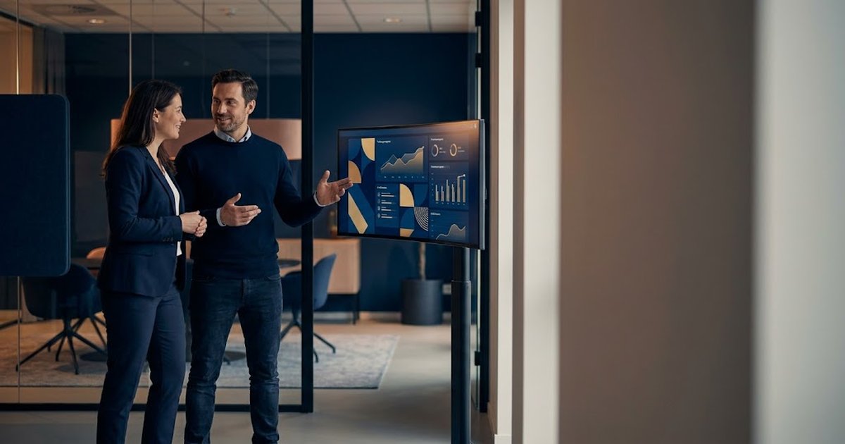 Partner enablement lead reviewing a partner-training dashboard with a colleague in a modern office