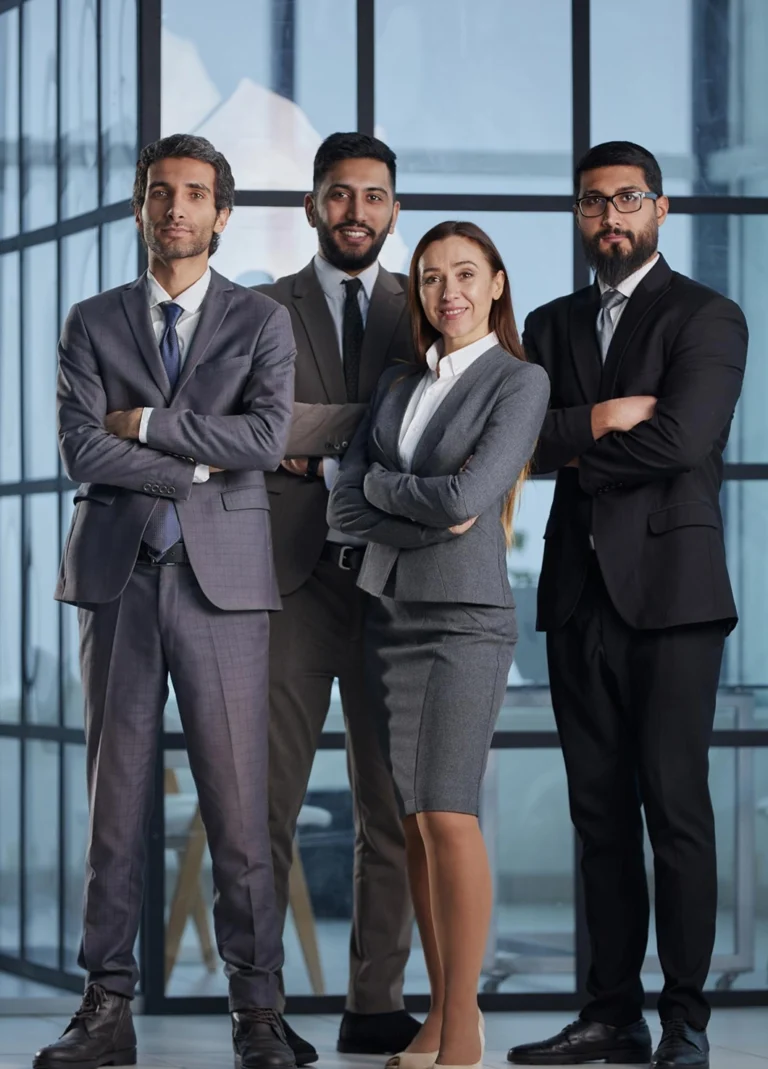 Four business professionals standing with arms crossed in a modern glass-walled office.**